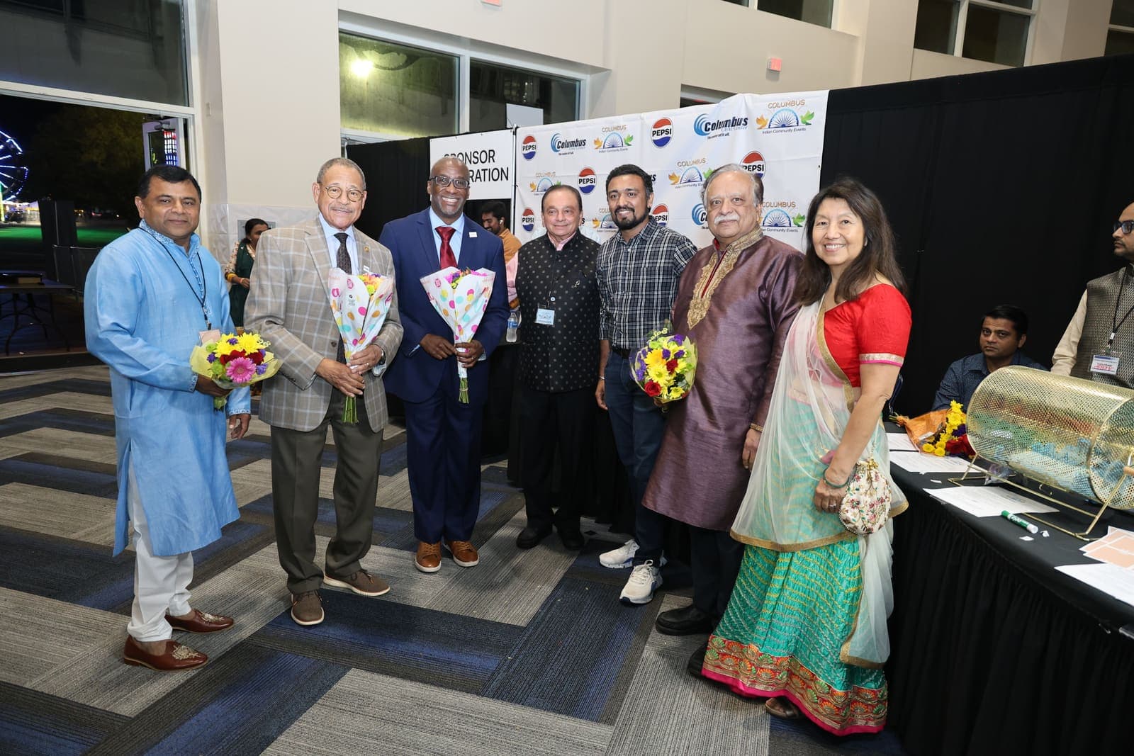 Community leaders and sponsors posing together with flowers
